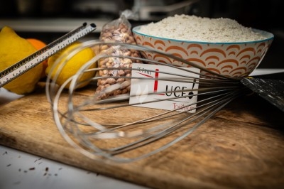 Bol de farine, fouet métallique, citrons, zesteur, beurre et noisettes posés sur une planche en bois.