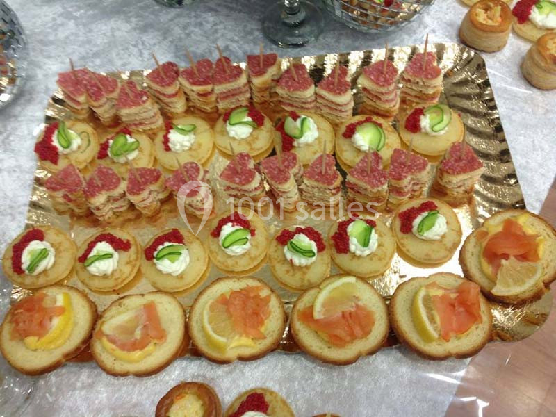 Plateau de canapés variés avec saumon fumé, citron, crème, concombre, tarama et charcuterie sur une table.