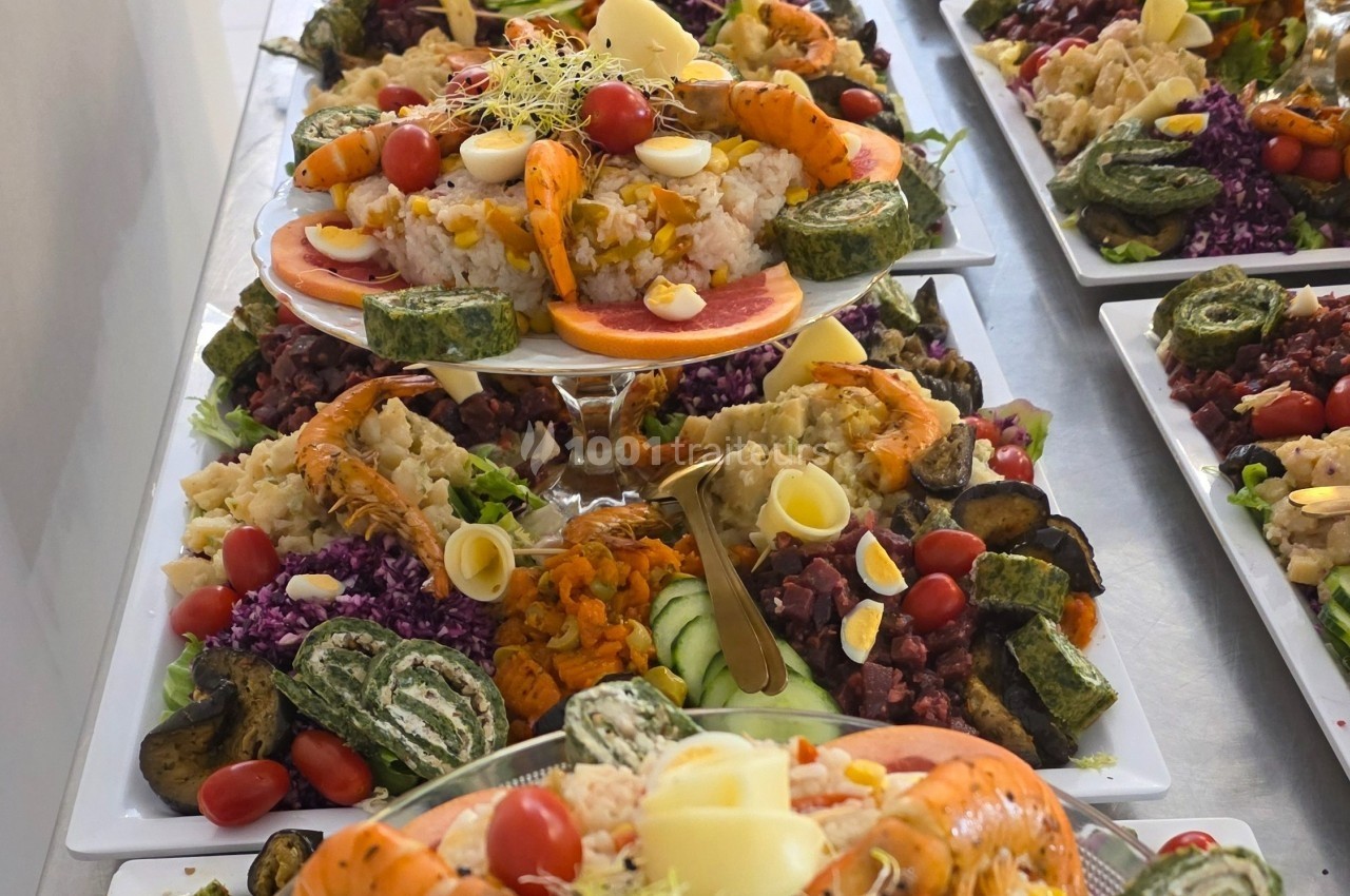 Plateaux garnis de divers aliments colorés, dont crevettes, œufs, légumes, roulés verts et salades variées.
