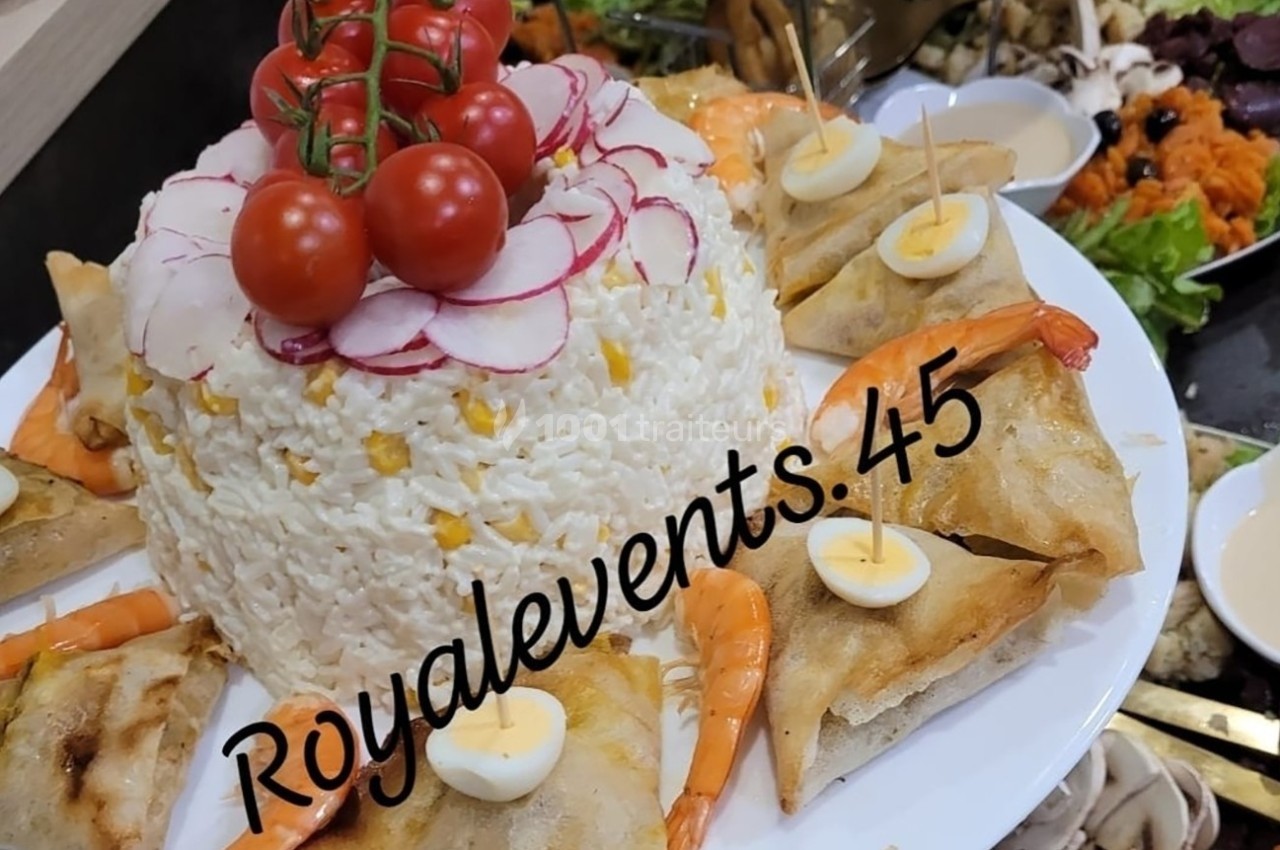Assiette garnie de riz décoré de radis et tomates cerises, entourée de samoussas, crevettes et œufs de caille.