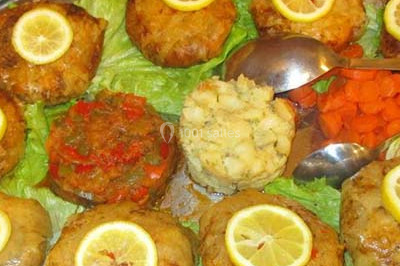 Assiette garnie de riz décoré de radis et tomates cerises, entourée de samoussas, crevettes et œufs de caille.