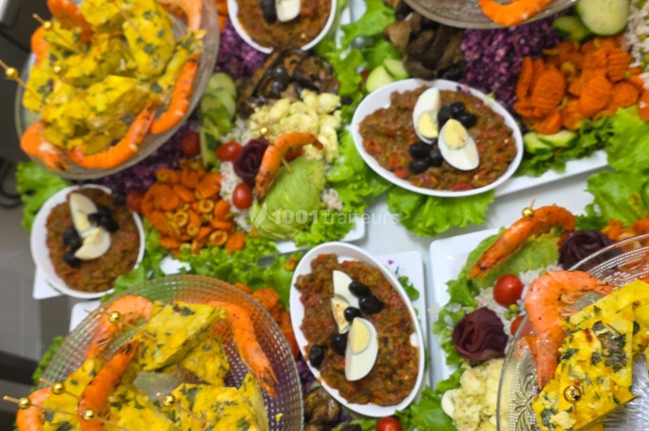 Assortiment de plats colorés comprenant crevettes, salades variées, légumes frais et garnitures décoratives.