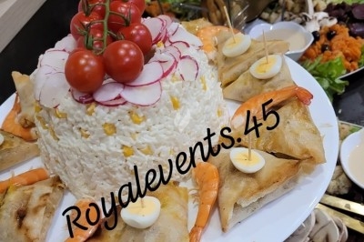 Assiette garnie de riz décoré de radis et tomates cerises, entourée de samoussas, crevettes et œufs de caille.
