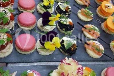 Dessert décoré avec des macarons, fraises, feuilles en chocolat, fleurs comestibles et touches de feuilles d'or.