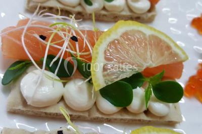 Dessert décoré avec des macarons, fraises, feuilles en chocolat, fleurs comestibles et touches de feuilles d'or.