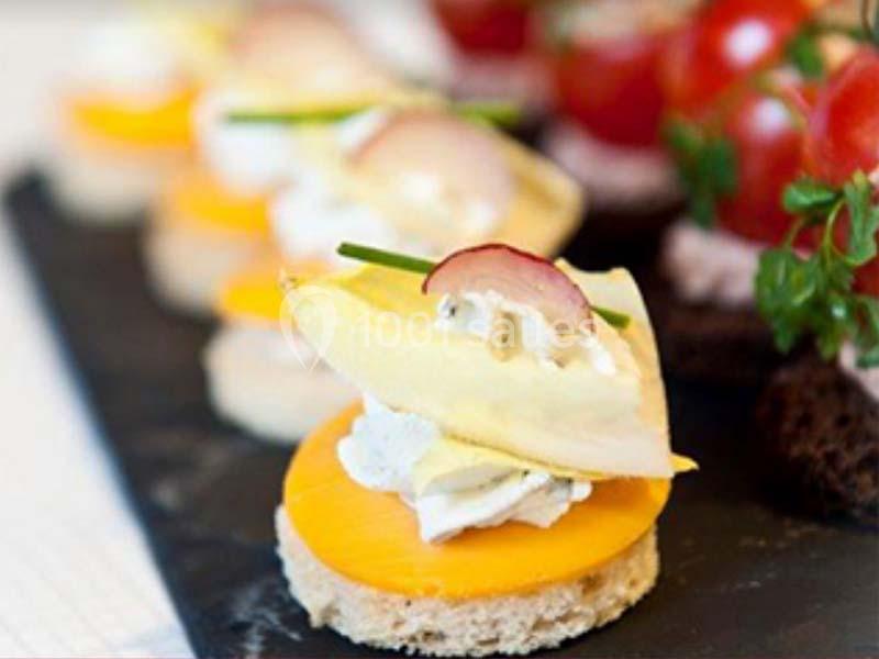 Assortiment de canapés garnis de fromage, légumes et herbes, disposés sur une ardoise noire.