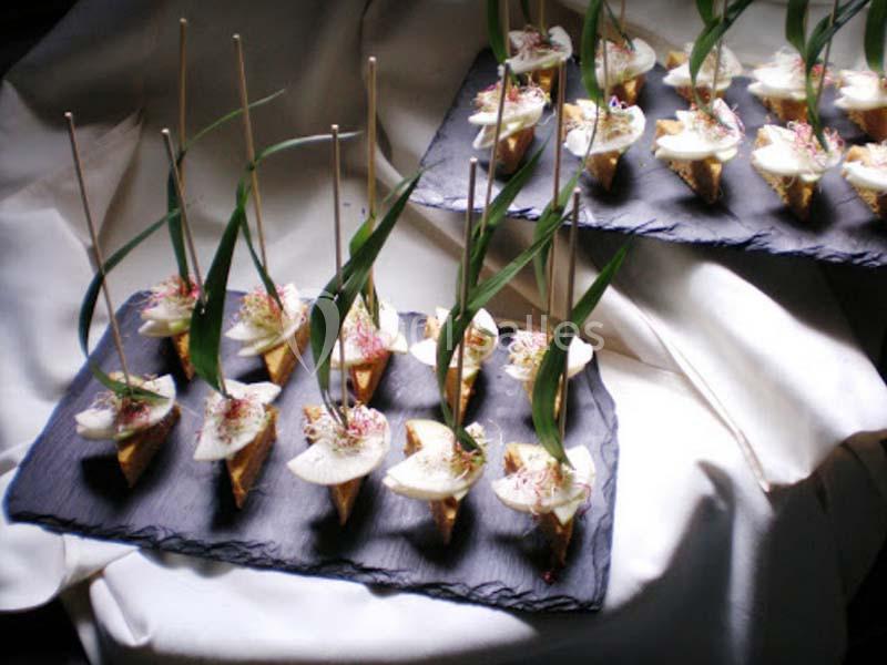 Petits cônes apéritifs garnis de fromage et décorés de pousses, présentés sur des plateaux en ardoise.