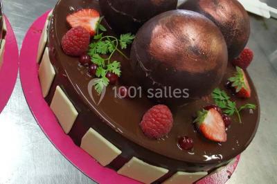 Dessert décoré avec des macarons, fraises, feuilles en chocolat, fleurs comestibles et touches de feuilles d'or.