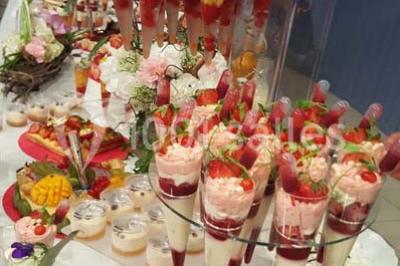 Dessert décoré avec des macarons, fraises, feuilles en chocolat, fleurs comestibles et touches de feuilles d'or.