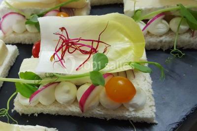 Dessert décoré avec des macarons, fraises, feuilles en chocolat, fleurs comestibles et touches de feuilles d'or.