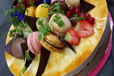 Dessert décoré avec des macarons, fraises, feuilles en chocolat, fleurs comestibles et touches de feuilles d'or.