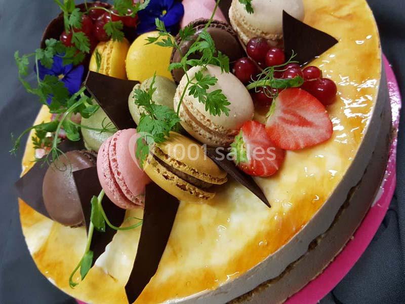 Gâteau décoré de macarons colorés, fraises, groseilles, feuilles de chocolat et herbes fraîches.