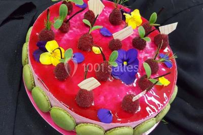 Dessert décoré avec des macarons, fraises, feuilles en chocolat, fleurs comestibles et touches de feuilles d'or.