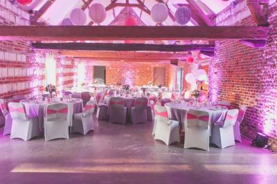 Tour en briques avec toit en ardoise, entourée de bâtiments ruraux et d'arbres, sous un ciel dégagé.