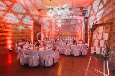 Tour en briques avec toit en ardoise, entourée de bâtiments ruraux et d'arbres, sous un ciel dégagé.