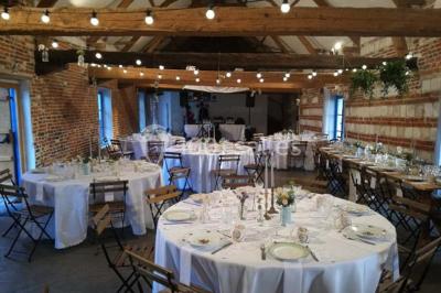 Tour en briques avec toit en ardoise, entourée de bâtiments ruraux et d'arbres, sous un ciel dégagé.