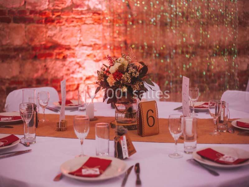 Table décorée pour un événement avec centre de table floral, nappes blanches et numéro de table 6.