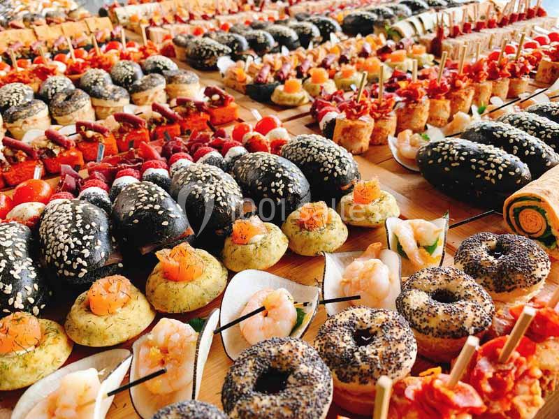 Plateau varié de bouchées apéritives colorées, incluant pains noirs, brochettes, crevettes et amuse-bouches garnis.