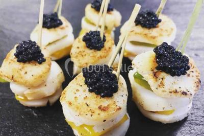 Gâteau à trois étages décoré de motifs dorés, plumes blanches et perles, avec une inscription d'anniversaire.