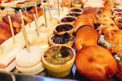 Gâteau à trois étages décoré de motifs dorés, plumes blanches et perles, avec une inscription d'anniversaire.