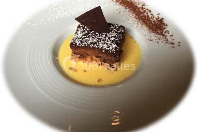 Gâteau à trois étages décoré de motifs dorés, plumes blanches et perles, avec une inscription d'anniversaire.