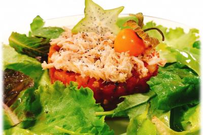 Gâteau à trois étages décoré de motifs dorés, plumes blanches et perles, avec une inscription d'anniversaire.