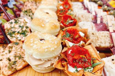 Gâteau à trois étages décoré de motifs dorés, plumes blanches et perles, avec une inscription d'anniversaire.