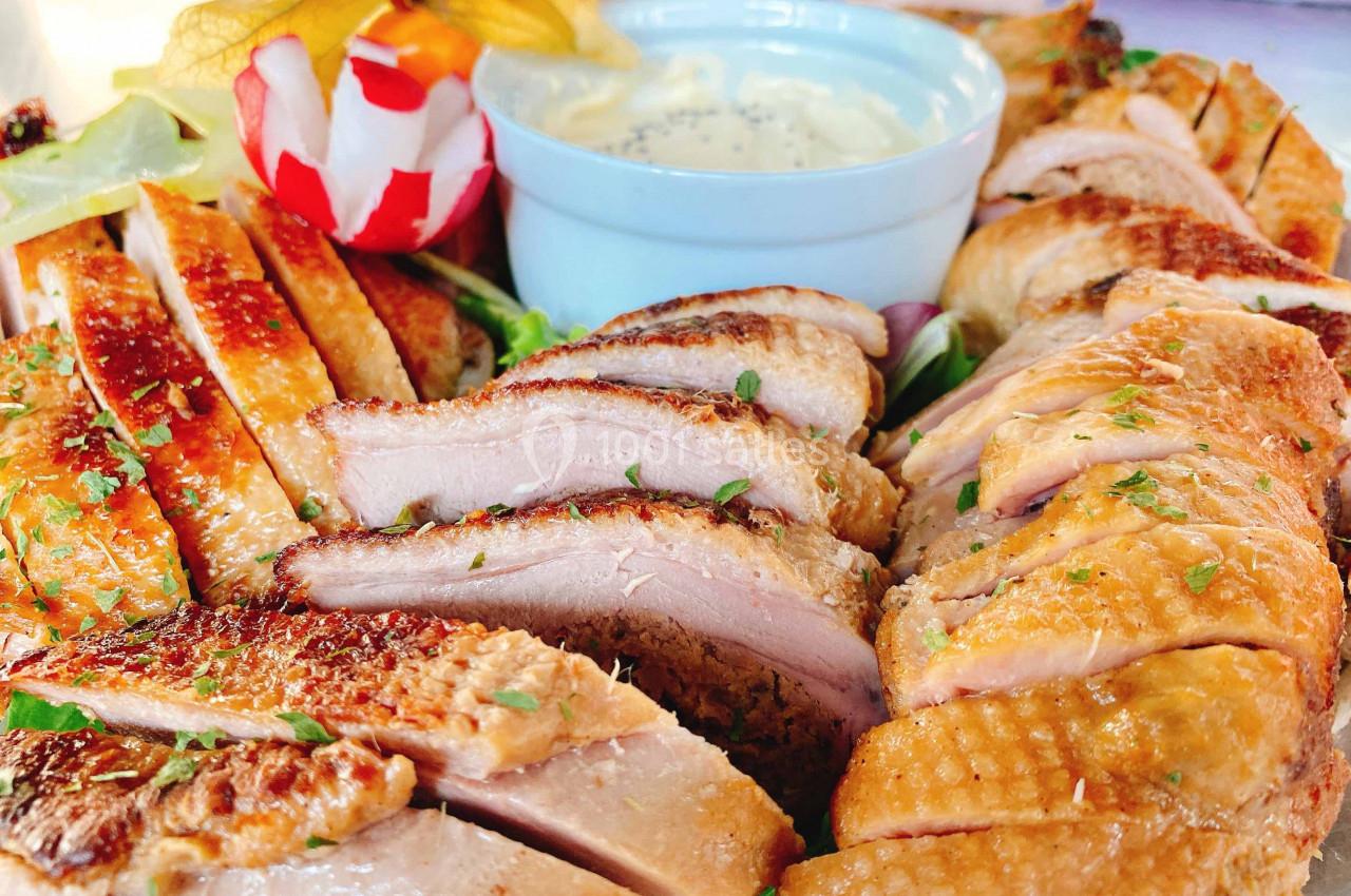 Assiette de magret de canard tranché, accompagné de sauce blanche et décoré de légumes et physalis.