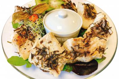 Gâteau à trois étages décoré de motifs dorés, plumes blanches et perles, avec une inscription d'anniversaire.