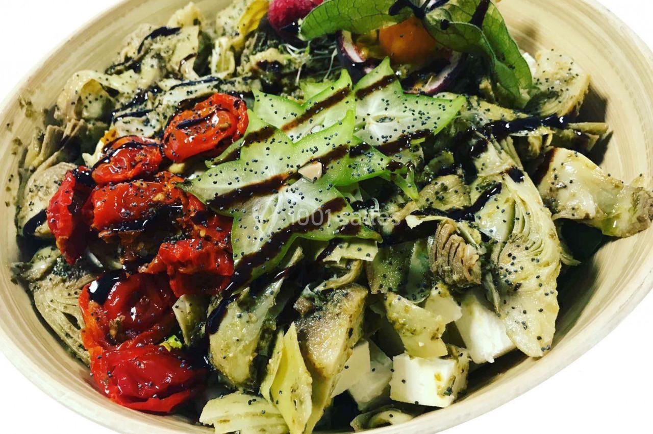 Salade composée avec artichauts, tomates confites, fromage, graines de pavot et filet de vinaigre balsamique.