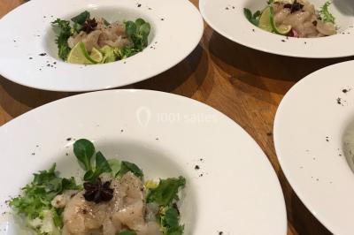 Gâteau à trois étages décoré de motifs dorés, plumes blanches et perles, avec une inscription d'anniversaire.