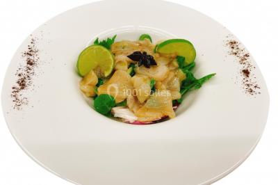 Gâteau à trois étages décoré de motifs dorés, plumes blanches et perles, avec une inscription d'anniversaire.