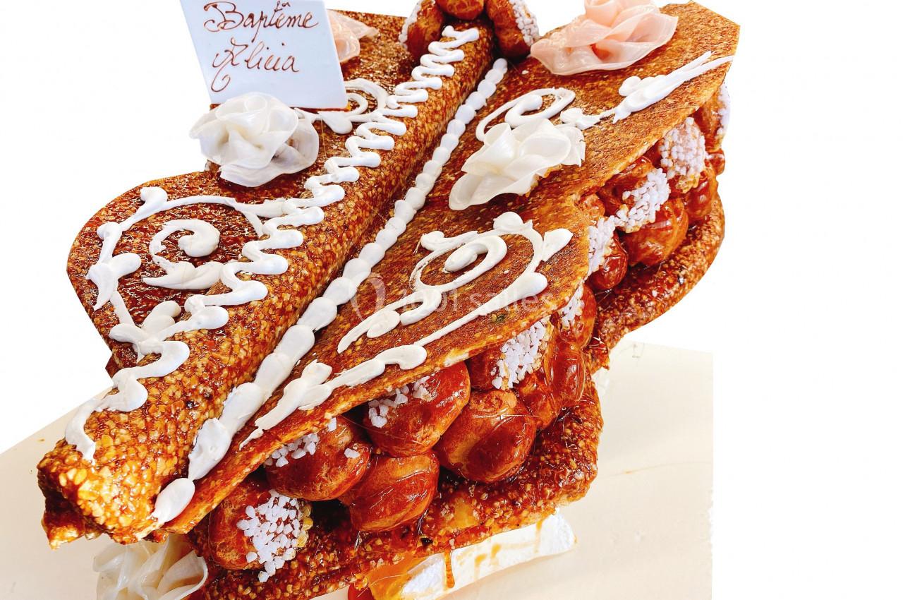 Pièce montée en choux caramélisés et décorations en sucre et crème, avec une étiquette manuscrite.