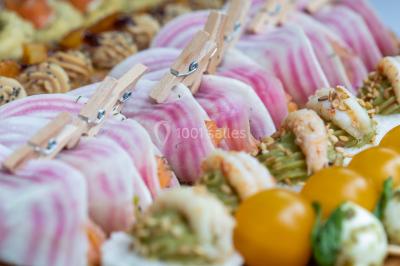 Gâteau à trois étages décoré de motifs dorés, plumes blanches et perles, avec une inscription d'anniversaire.