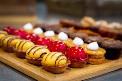 Gâteau à trois étages décoré de motifs dorés, plumes blanches et perles, avec une inscription d'anniversaire.