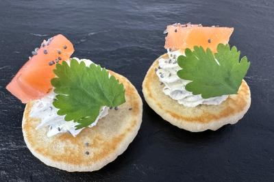Gâteau à trois étages décoré de motifs dorés, plumes blanches et perles, avec une inscription d'anniversaire.
