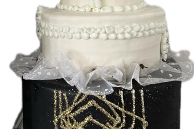 Gâteau à trois étages décoré de motifs dorés, plumes blanches et perles, avec une inscription d'anniversaire.