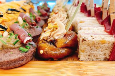 Logo d'un traiteur avec silhouette de chef et couverts, accompagné de photos de bouchées et plats variés colorés.