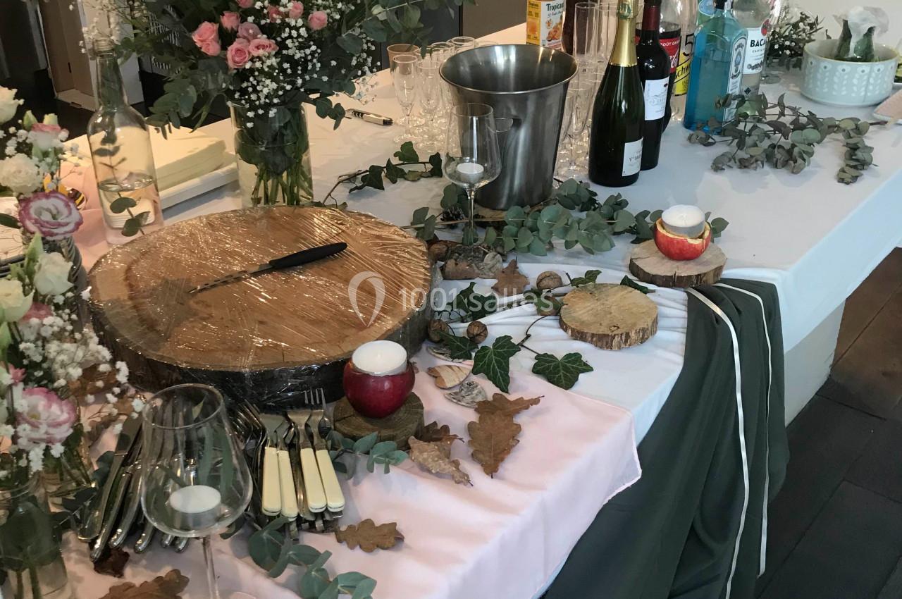 Table décorée pour un buffet avec fleurs, boissons, verres, planches en bois et couverts disposés.