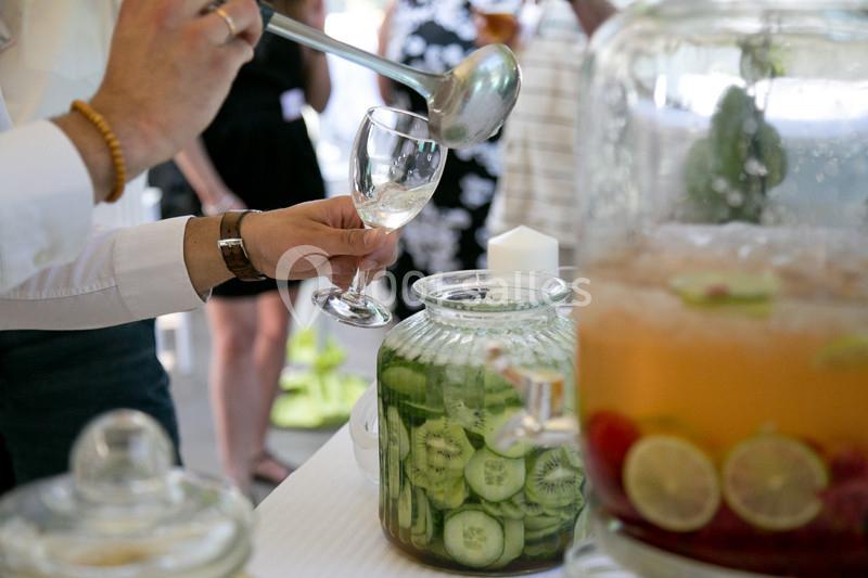 Une personne sert une boisson à base de concombre dans un verre lors d'un buffet avec des boissons infusées.