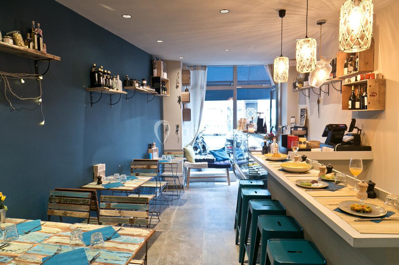 Intérieur d'un petit café moderne avec des tables en bois, un comptoir, des tabourets et une décoration lumineuse.