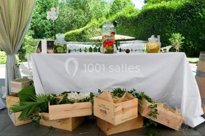 Une femme souriante se tient derrière un stand de produits variés dans une salle décorée avec un sapin de Noël.
