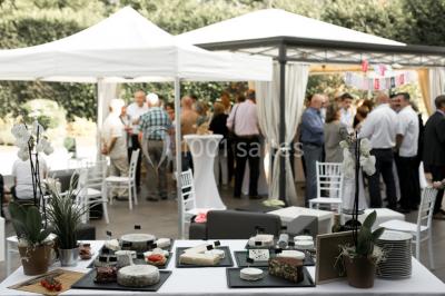 Une femme souriante se tient derrière un stand de produits variés dans une salle décorée avec un sapin de Noël.