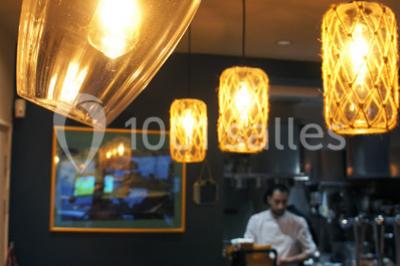 Une femme souriante se tient derrière un stand de produits variés dans une salle décorée avec un sapin de Noël.
