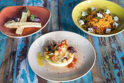 Une femme souriante se tient derrière un stand de produits variés dans une salle décorée avec un sapin de Noël.