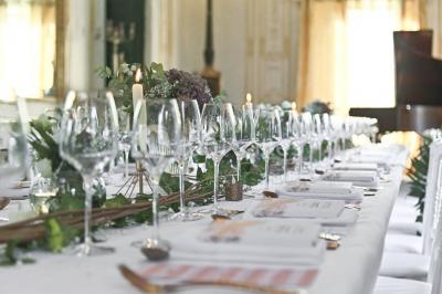Une femme souriante se tient derrière un stand de produits variés dans une salle décorée avec un sapin de Noël.