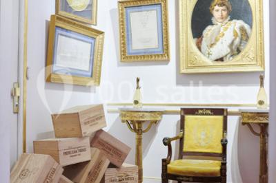 Une femme souriante se tient derrière un stand de produits variés dans une salle décorée avec un sapin de Noël.