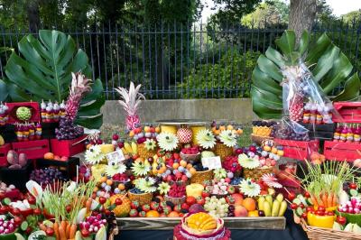 Une femme souriante se tient derrière un stand de produits variés dans une salle décorée avec un sapin de Noël.