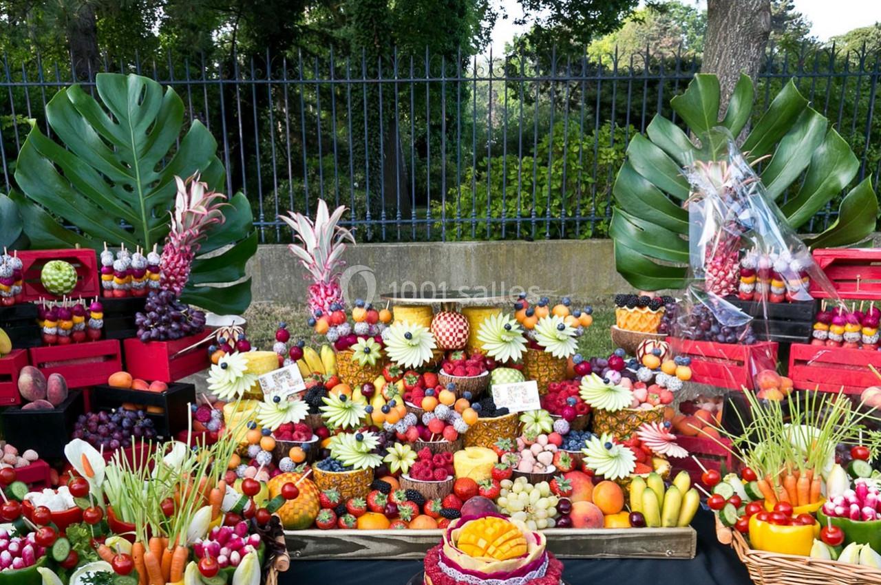 Présentation colorée de fruits variés et découpés, disposés sur une table avec des feuilles tropicales en arrière-plan.