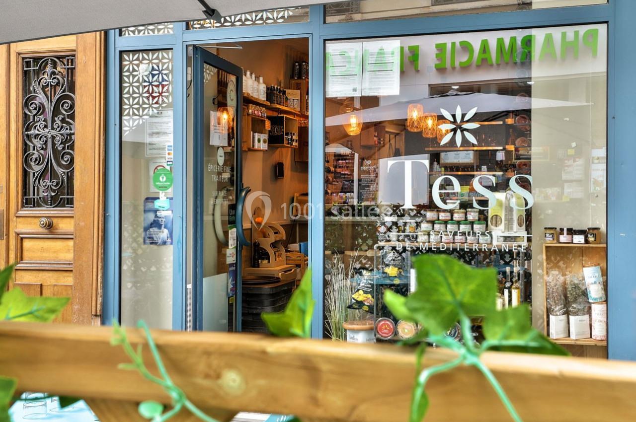 Façade d'une boutique avec vitrine affichant ’Tess’, entourée de plantes et d'éléments de décoration extérieure.